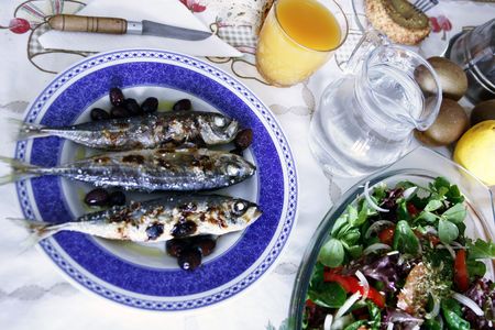 On the table, grilled mackerels poured with olive oil, oranje juice and bread.の写真素材