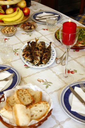 On the table, grilled mackerels poured with olive oil, water, fruit, salad and bread.の写真素材