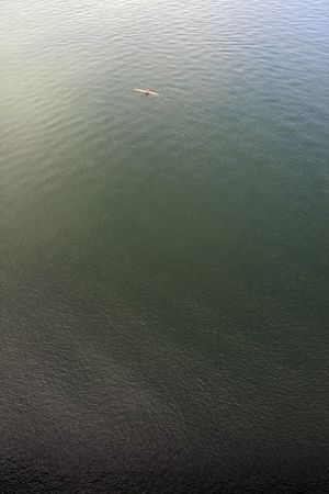 View of a single man on a canoe on a vast area of water.