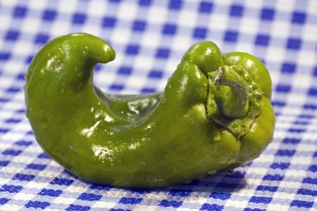 Weird formed green bell pepper vegetable isolated on the kitchen table.の写真素材