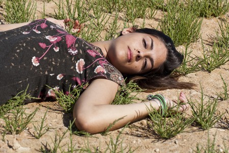 Beautiful girl with floral dress on the ground in a sunny day.の写真素材
