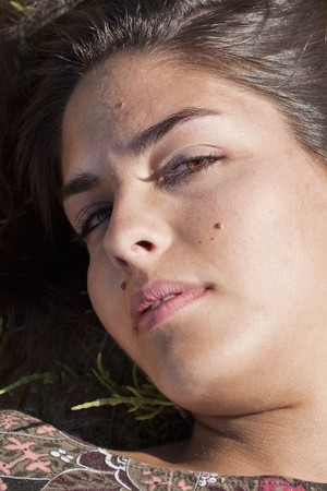 Beautiful girl with floral dress on the ground in a sunny day.の写真素材