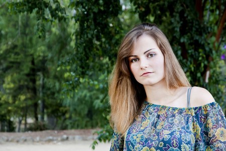 View of a beautiful girl on a floral dress on a park.の写真素材