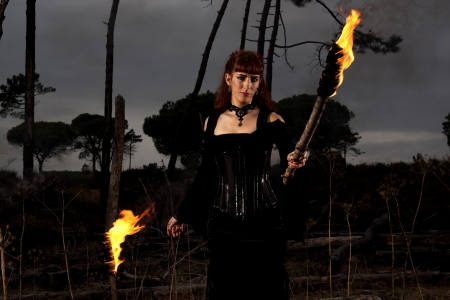 View of a dark clothed woman with a torch on her hands.の写真素材
