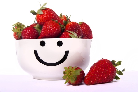 View of a smiley bowl filled with strawberries isolated on a white background.の写真素材