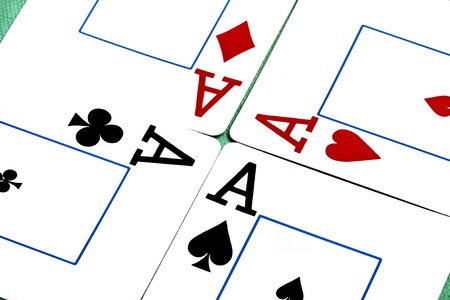 Close up view of a set of four aces spread on a green cloth table.