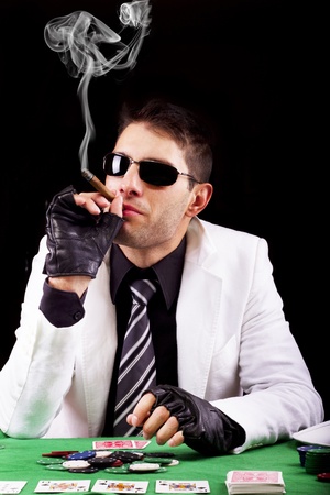 View of a gangster man playing some cards and poker, smoking a Cuban cigar.のeditorial素材