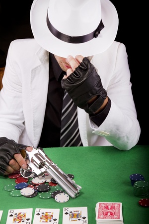 View of a gangster man playing some cards and poker, holding a gun.のeditorial素材