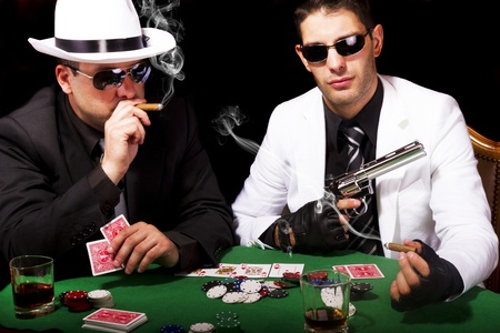 View of two gangster males playing some poker and smoking Cuban cigars.のeditorial素材