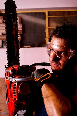 View of a garage mechanic man holding a chainsaw.の写真素材