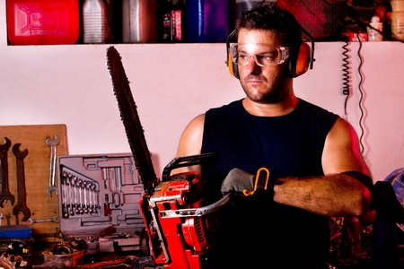 View of a garage mechanic man holding a chainsaw.の写真素材