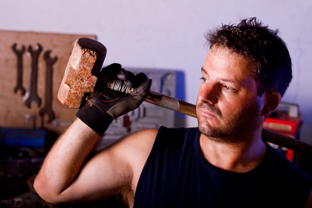 View of a garage mechanic man holding a big hammer.の写真素材