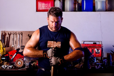 View of a garage mechanic man holding a big hammer.の写真素材
