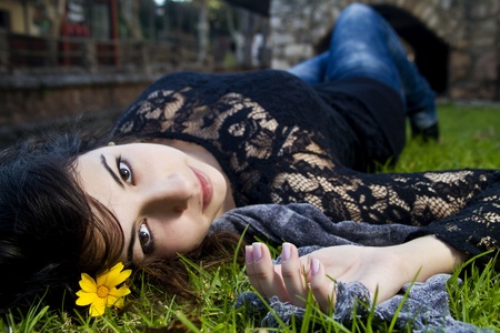Beautiful young girl lies down on the green grass on a urban park.の写真素材
