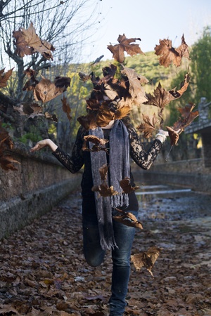 Beautiful girl throws in the air a bunch of autumn leaves.の写真素材