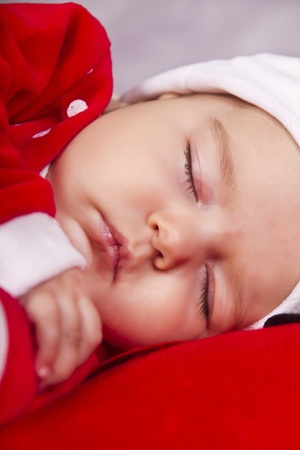 View of a newborn baby on a Christmas suit sleeping.の写真素材