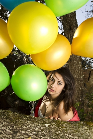 View of a beautiful girl with balloons next to a tree.の写真素材