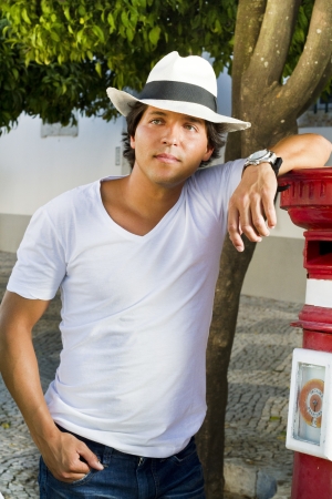 View of a handsome man with white shirt and hat on a urban city.の写真素材