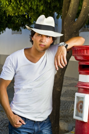 View of a handsome man with white shirt and hat on a urban city.の写真素材
