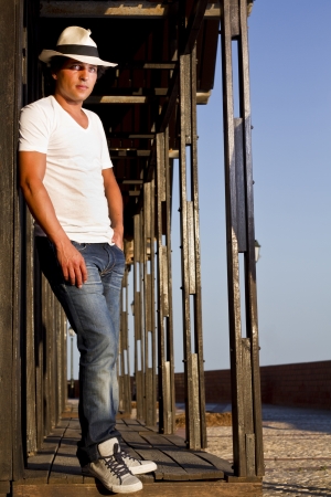 View of a handsome man with white shirt and hat on a urban city.の写真素材