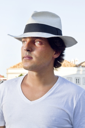 View of a handsome man with white shirt and hat on a urban city.の写真素材