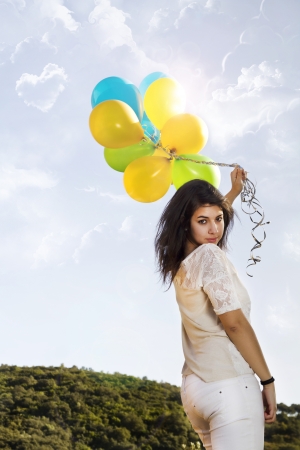 View of a beautiful girl with balloons next to a tree.の写真素材