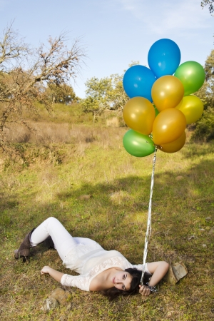 View of a beautiful girl with balloons next to a tree.の写真素材