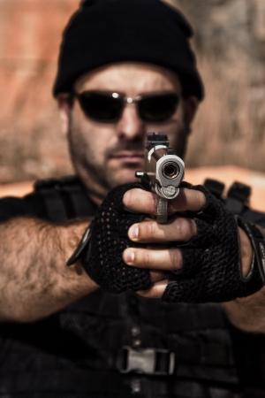 View of a man with dark shades pointing a gun to the camera.の写真素材