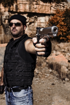 View of a man with dark shades pointing a gun to the camera.の写真素材