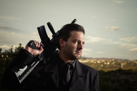View of a contracted type killer agent wandering with a long jacket and machine gun.