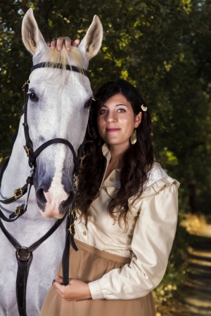 View of a beautiful girl in classic dress with a white horse on the countryside.の写真素材