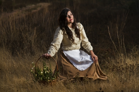 View of a beautiful girl in classic dress wandering on the countryside.