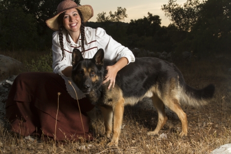 View of a beautiful girl in a classic dress in a countryside set with a dog.の写真素材