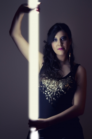 View of a beautiful girl in dark leather clothes holding a light tube.の写真素材