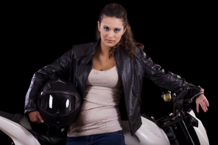 View of a beautiful young girl next to a white motorbike in a studio environment. の写真素材
