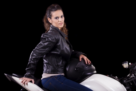 View of a beautiful young girl next to a white motorbike in a studio environment. の写真素材