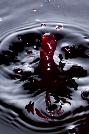 Close view of a droplet of wine hitting a surface of wine. の写真素材