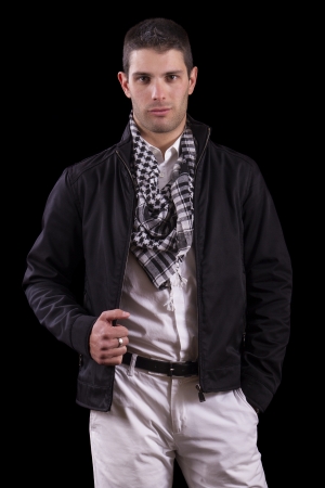 View of a young urban styled fashioned man standing isolated on a black background.の写真素材