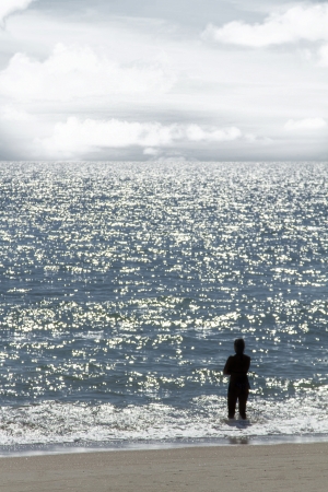View of a lonely silhouette of a person staring at the immense ocean.の写真素材