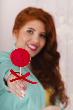 View of a beautiful redhead girl with a lollipop candy wearing colorful clothing.
