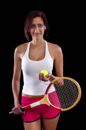 Beautiful young girl with a tennis racquet on a black background.の写真素材