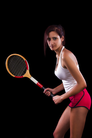 Beautiful young girl with a tennis racquet on a black background.の写真素材