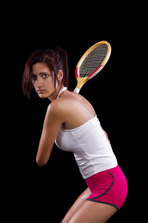 Beautiful young girl with a tennis racquet on a black background.の写真素材