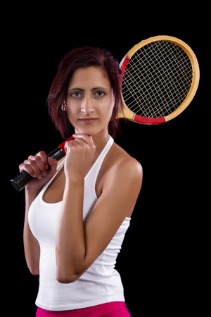 Beautiful young girl with a tennis racquet on a black background.の写真素材