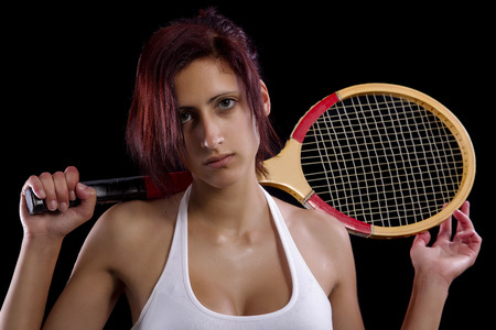 Beautiful young girl with a tennis racquet on a black background.の写真素材