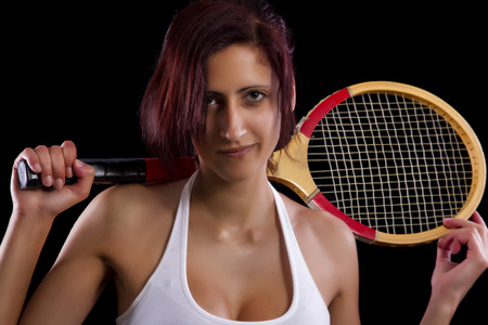 Beautiful young girl with a tennis racquet on a black background.の写真素材