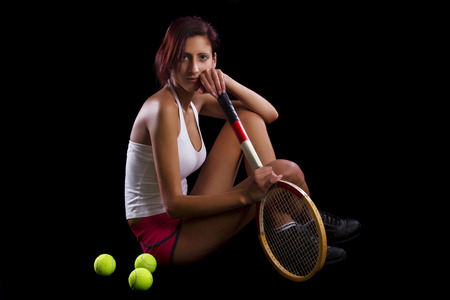 Beautiful young girl with a tennis racquet on a black background.の写真素材