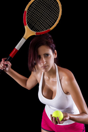 Beautiful young girl with a tennis racquet on a black background.の写真素材