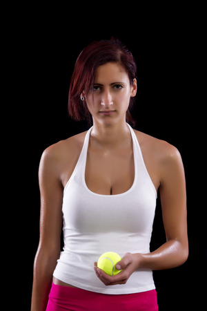 Beautiful young girl with a tennis racquet on a black background.の写真素材