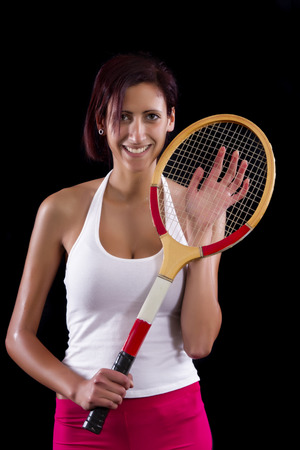 Beautiful young girl with a tennis racquet on a black background.の写真素材